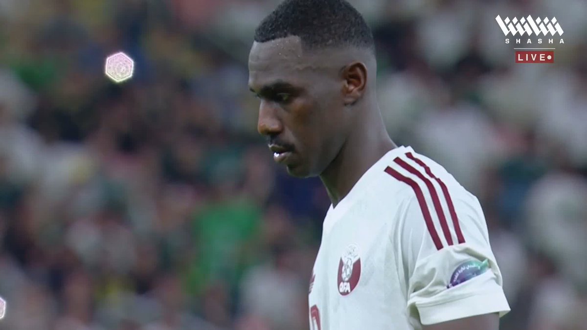 A close-up of a soccer player in a white Qatar jersey with maroon stripes, with the 'SHASHA LIVE' logo visible in the upper right corner.