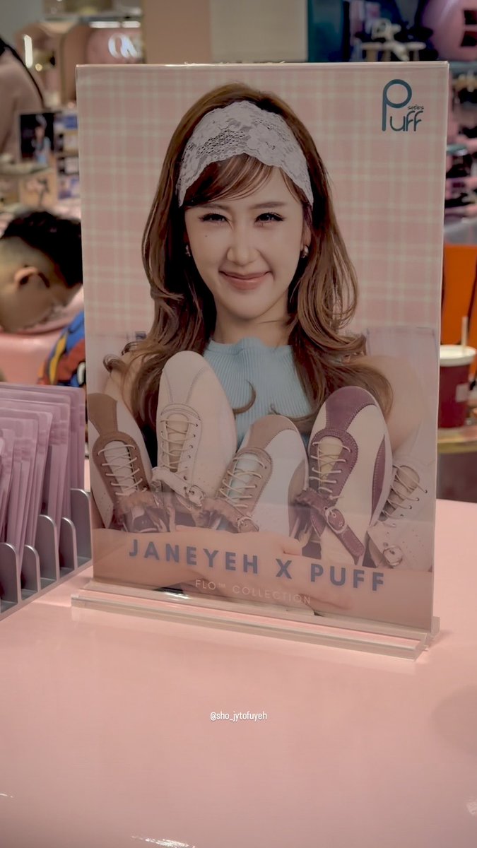 An in-store advertisement displays a smiling woman with a white lace headband holding ballet shoes, with text reading 'JANEYEH X PUFF FLO COLLECTION' and the Puff Shoes logo.
