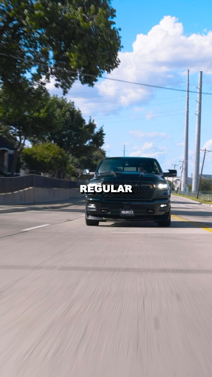 A black pickup truck drives down a road toward the camera with the word 'REGULAR' overlaid in white text across the vehicle.