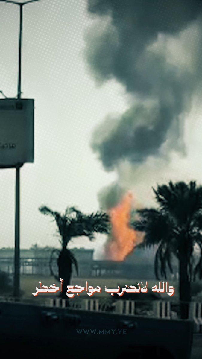 A photo of a large plume of black smoke rising from a fire near palm trees and industrial structures, with Arabic text at the bottom reading 'والله لانضرب موج أخطر' and the watermark 'www.mmy.ye'.
