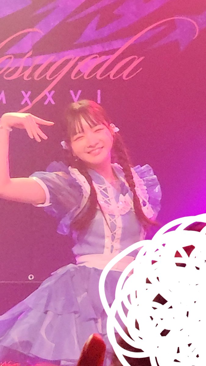 A performer in a blue dress with pigtails strikes a peace pose on a pink-lit stage with the text 'Kasuga' and 'XXXVI' displayed behind her.