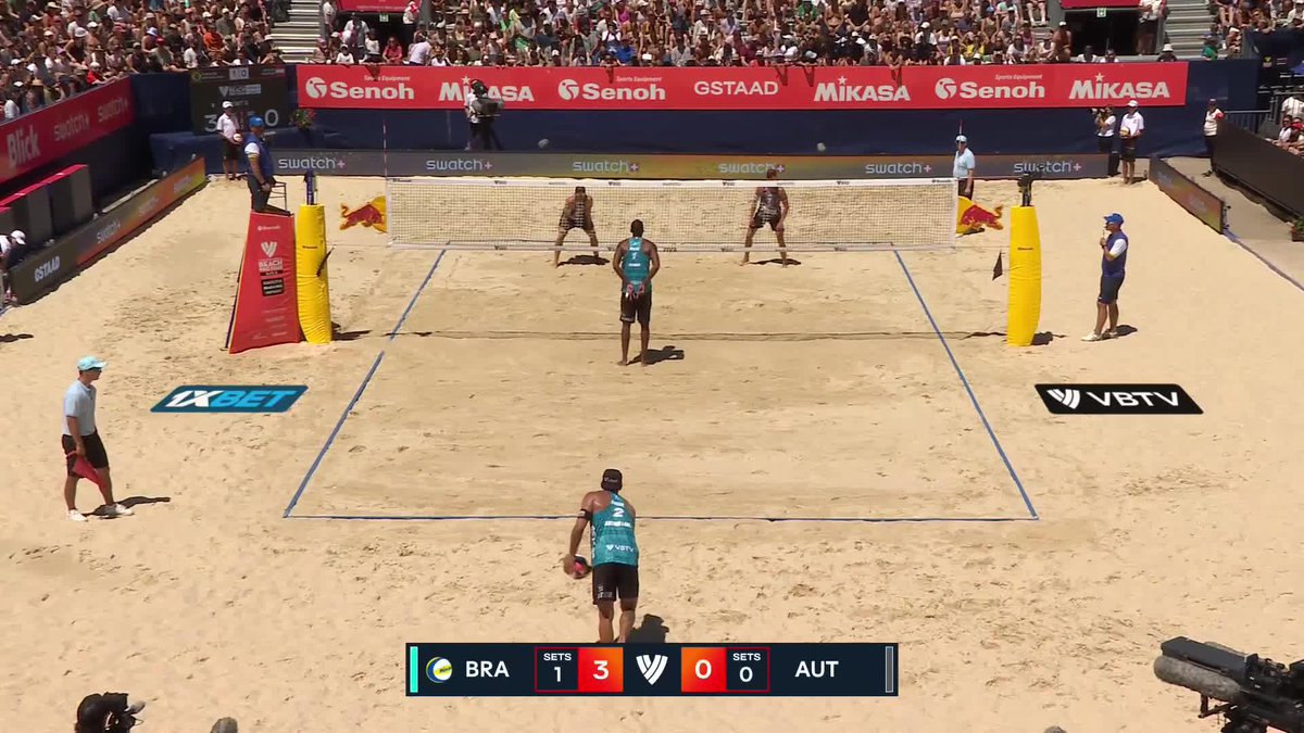 A beach volleyball match between Brazil (BRA) and Austria (AUT) is underway, with Brazil leading 3 sets to 0, as players from Arthur Lanci and Evandro's team prepare to defend against their Austrian opponents on the sand court surrounded by sponsor banners including Senoh, Mikasa, and Swatch.