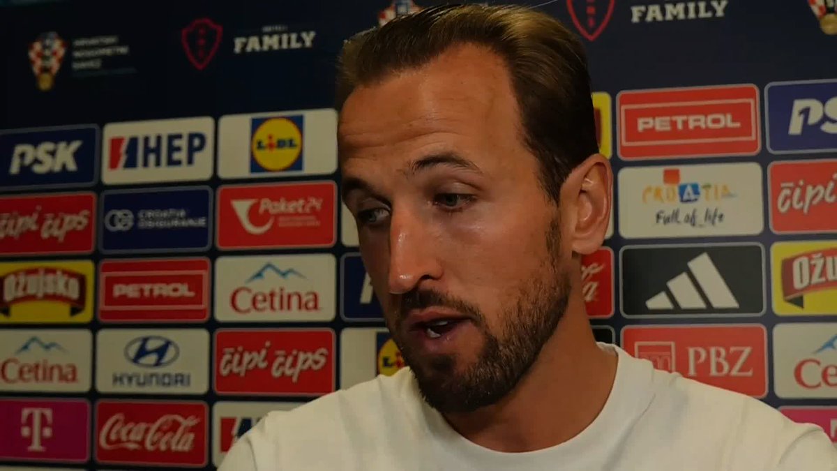 Harry Kane speaks during a post-match interview in front of a sponsor backdrop featuring brands like Lidl, HEP, Coca-Cola, Hyundai, and Adidas, discussing his future with England.