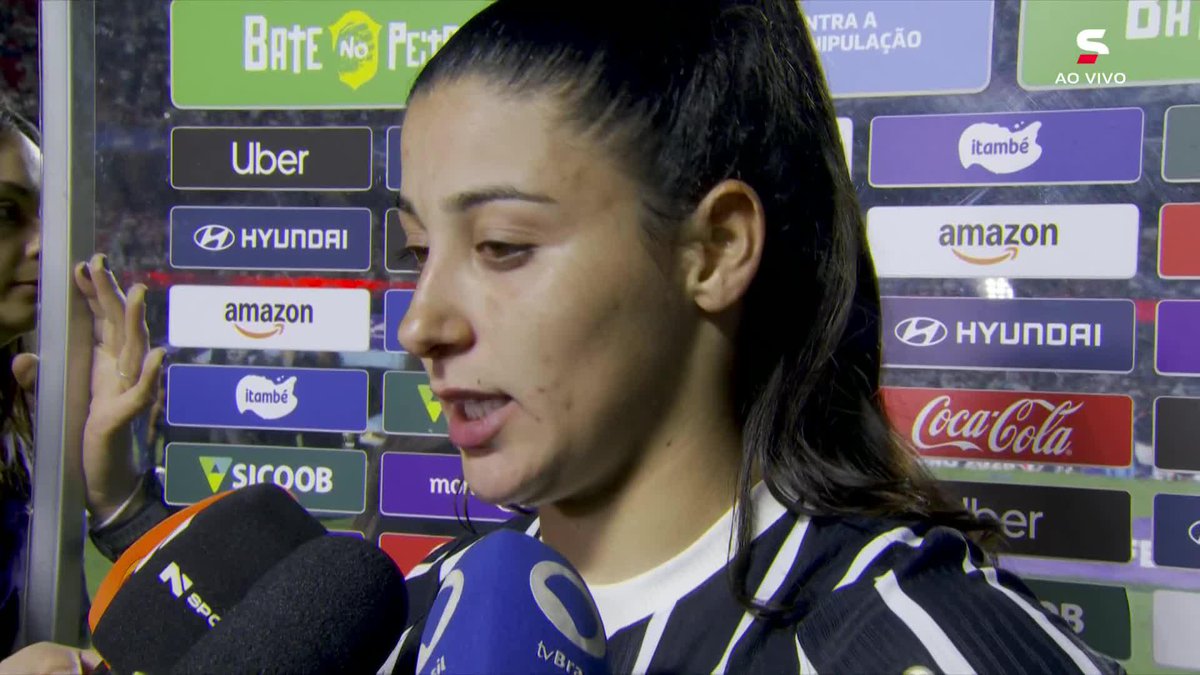 Duda Sampaio is interviewed by Brazilian media outlets (SPC and TV Brasil) in front of a sponsor backdrop featuring Hyundai, Amazon, Coca-Cola, Uber, and Sicoob, consistent with a post-match press setting following Corinthians' runner-up finish in the Women's Brasileirão.