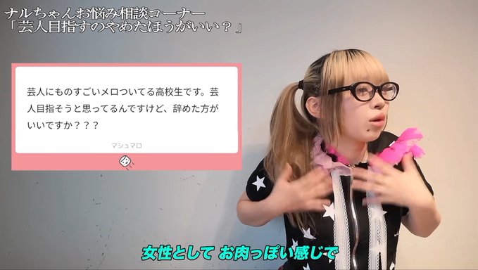 The image shows a blonde woman with pigtails and glasses, wearing a black star-patterned outfit with a pink feather boa, gesturing while speaking. Japanese text appears on screen, including a pink consultation box with text addressed to "マシマロ" (Mashimaro) and the subtitle "女性として お肉っぽい感じで" ("a meaty/curvy feeling as a woman"). The scene relates to the post's caption by illustrating the awkward phrasing about being desired in a "meaty" way as a woman, which the poster found unsettling.