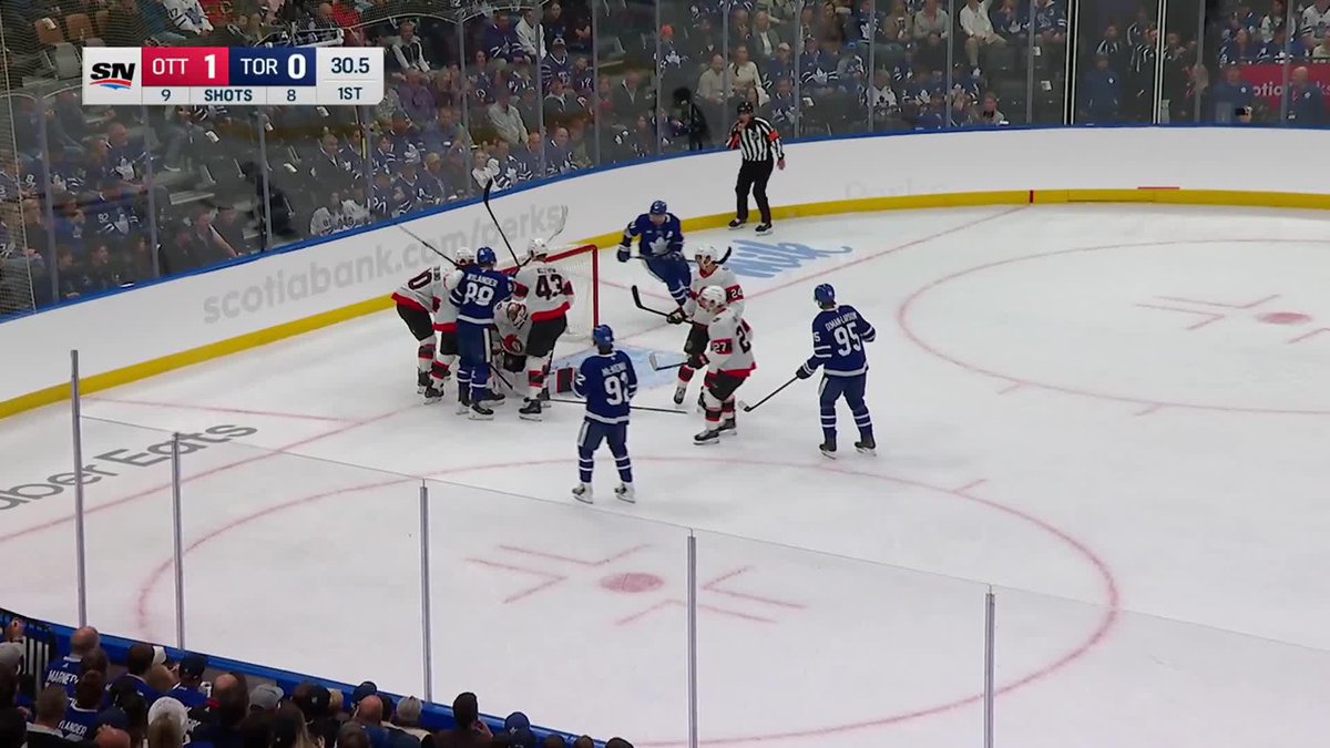 A scrum of players from the Ottawa Senators and Toronto Maple Leafs crowds the crease area during the final seconds of the 1st period, with the scoreboard showing Ottawa leading 1-0 (shots 9-8) with 30.5 seconds remaining. Sens captain Thomas Chabot (likely #72) is among the white-jerseyed players celebrating near the net, corresponding to the post announcing his first goal as team captain.