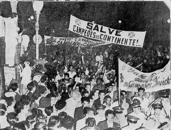 A black-and-white historical photograph of a large crowd holding banners reading 'SALVE CAMPEÕES DO CONTINENTE!' celebrating continental champions.