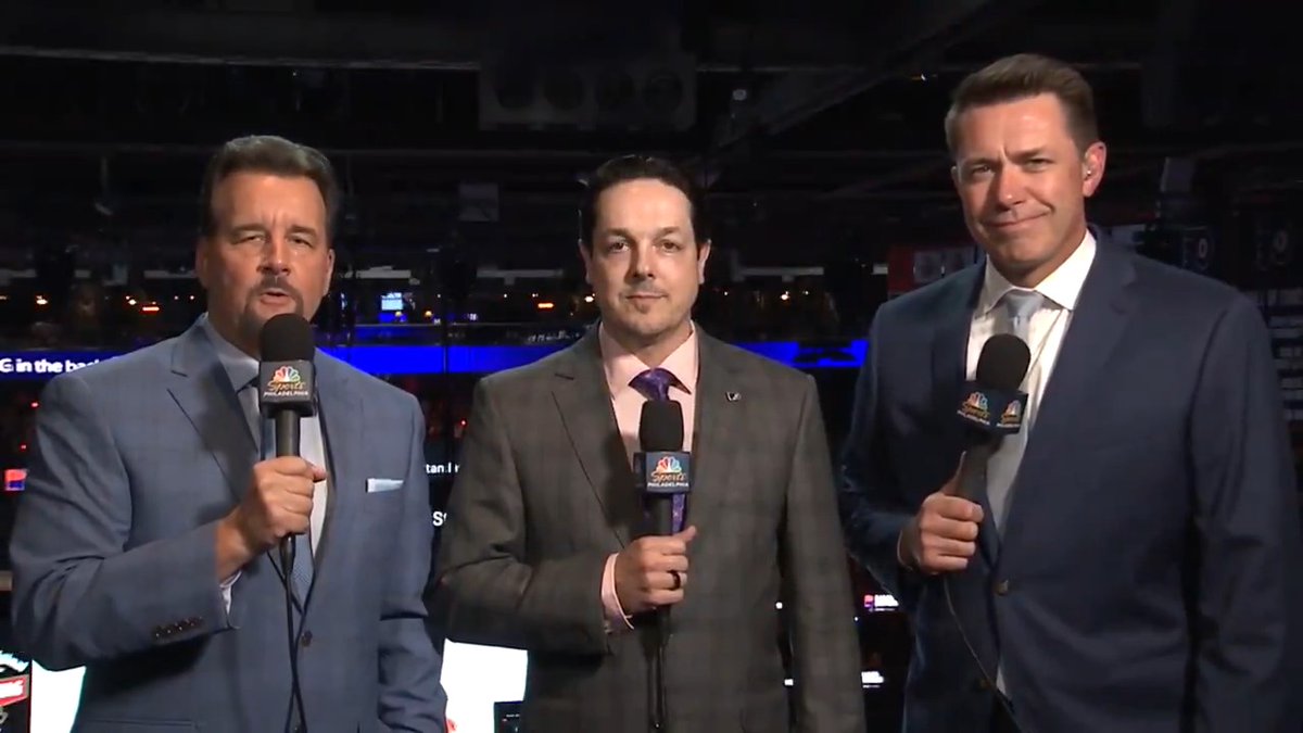 Three men in suits stand together holding NBC Sports microphones, with Daniel Briere in the middle flanked by two broadcasters during a first intermission segment. The "NBC Sports Philadelphia" logos are visible on the mics, and the arena setting behind them relates to the Philadelphia Flyers hockey game.