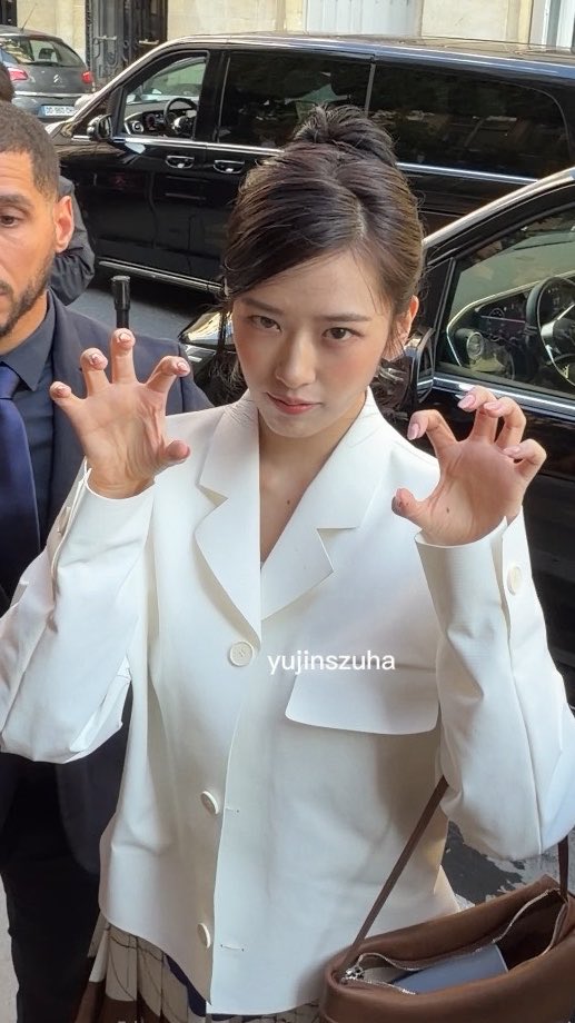 A young woman in a white blazer poses with clawed hands in front of black cars, with the watermark 'yujinszuha'.