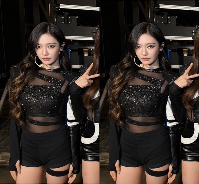 Two identical side-by-side images of a K-pop performer with long dark wavy hair, wearing a black sparkly sheer top and black shorts, posing with a peace sign.