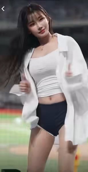 A young woman with long dark hair stands on a sports field wearing a white tank top, a black mini skirt, and an open white shirt.