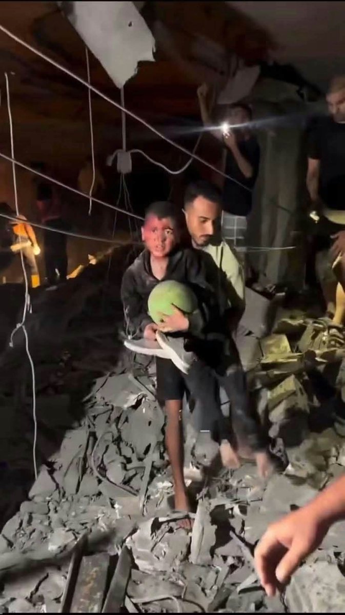 PalPress24's tweet photo. A photo of this child stopped me in my tracks. After being pulled from beneath the rubble of his home, he thought of nothing but his toy.

He emerged from the rubble and carnage carrying his ball and shoes, as if the war had failed to take away his childhood.

The child was pulled from the ruins following a strike in Gaza City yesterday that killed five Palestinians.

In Gaza, even children emerge from the rubble searching for something small that reminds them they are still children.