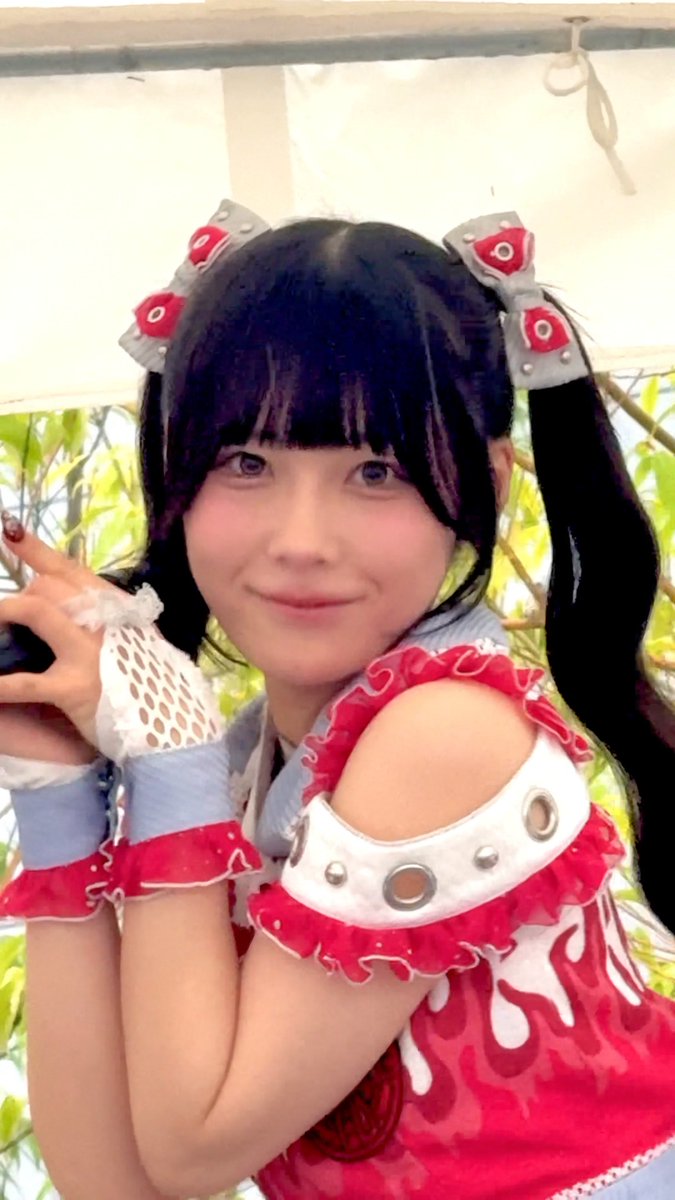 A cosplayer with dark twin-tails and red-and-white accessories smiles at the camera while posing in a pink and white frilled outfit, perfectly matching the affectionate "totally love it т_т♡" caption.