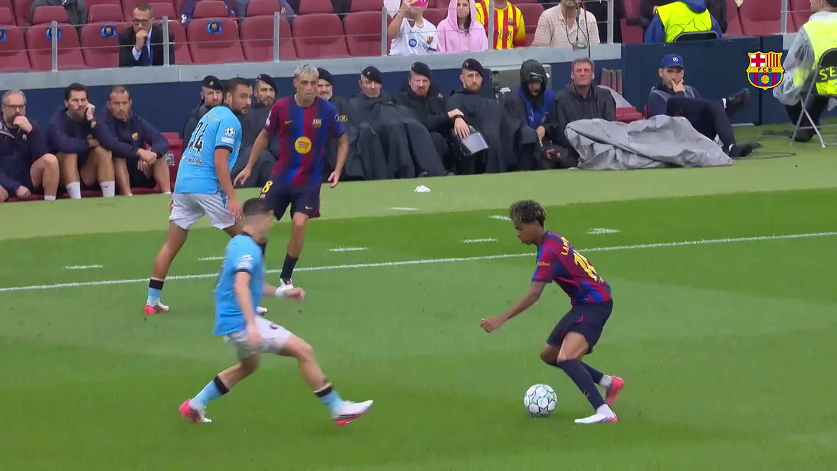 A soccer match scene showing FC Barcelona players in their iconic blue and red striped jerseys competing against an opposing team, with the FCB logo visible in the corner.