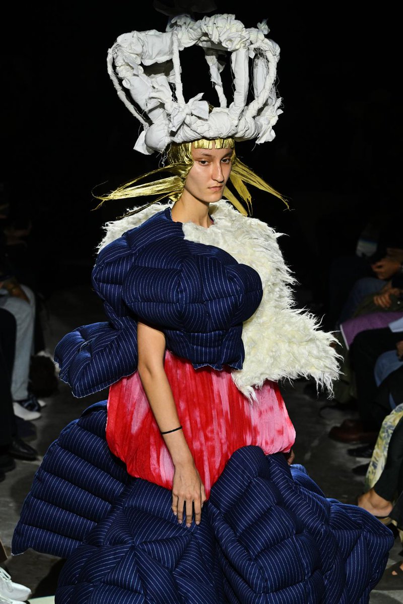 fashionsnap's tweet photo. 川久保玲が手掛ける「コム デ ギャルソン（COMME des GARÇONS）」の2027年春夏コレクションショーは、平穏な日常のモチーフと過剰な造形が衝突し、衣服の構造そのものが歪められていく連続であった。

　今季掲げられた「When royal life and everyday life become one（王族の暮らしと日常がひとつになるとき）」というテーマの裏には、美の追求というよりむしろ、人間の剥き出しの生をえぐり出すような冷徹な眼差しが潜んでいる。この言葉を文字通りに受け取り、単なる「権威に対するカウンターの表明」と結論づけるのは早計だろう。川久保が試みたのは、王族という虚飾と、日常という凡庸な現実を衝突させ、その境界線を破綻させることで、衣服の奥底に潜む人間の生々しい本性を浮き彫りにすることだったのではないか。
