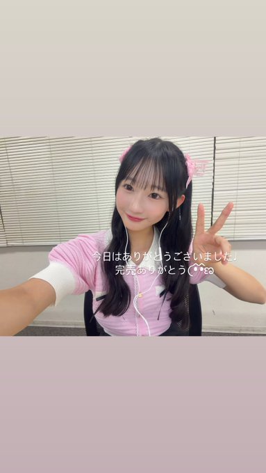 A young Asian woman with dark hair and pink hair clips makes a peace sign, wearing a pink top with earphones; Japanese text overlay reads '今日はありがとうございました！完売ありがとうございました♡' (Thank you for today! Thank you for the sold-out event).
