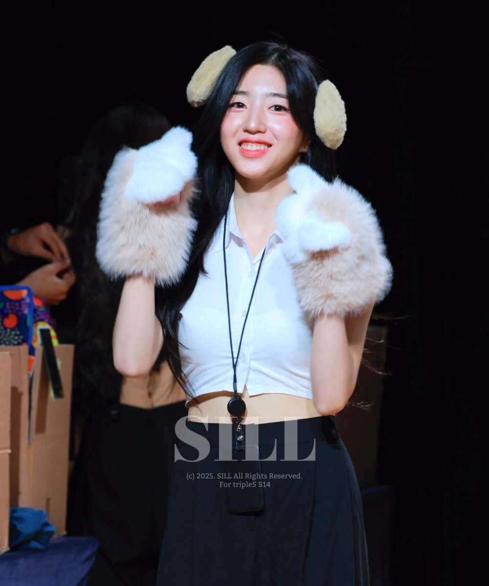 A smiling woman with long dark hair wears fluffy bear-ear headbands and matching paw gloves while holding up her hands; the image is watermarked with 'S14' and '(c) 2025. SILL All Rights Reserved. For tripleS S14'.
