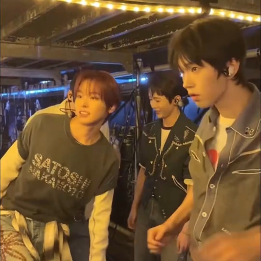 Three young male performers stand backstage, each wearing earpieces and casual stage attire—one in a "SATO SEI MEXICO" graphic t-shirt, another in a Western-style embroidered shirt, and the third in a denim top. The warm stage lighting and behind-the-scenes setting align with the post about "Jelies" at the a-nation 2024 event on October 4, 2024.