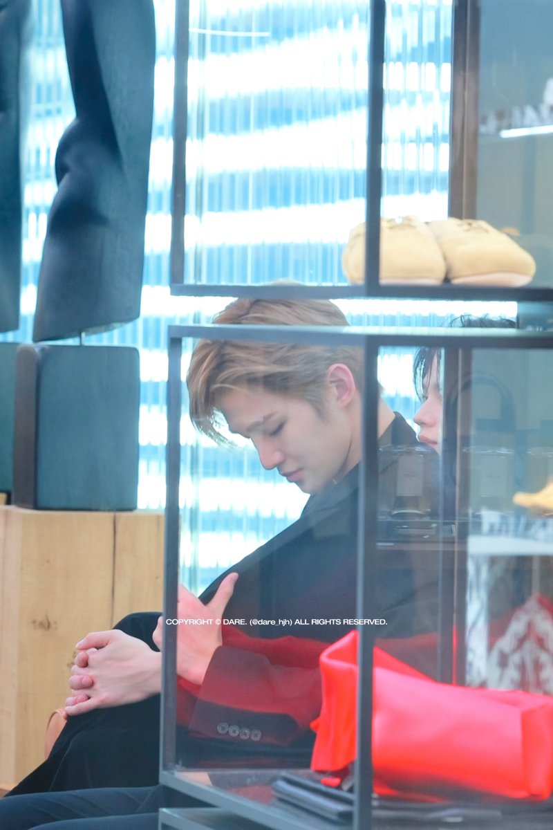 The image shows a person with brown hair in a dark suit sitting with head bowed, hands clasped, viewed through a glass display case, with another person partially visible beside them; a watermark reads "COPYRIGHT © DARE. (idure.hj) ALL RIGHTS RESERVED." The contemplative, intimate moment captured reflects the post's sentiment of being surprised and grateful for a rare chance to quietly share time together.