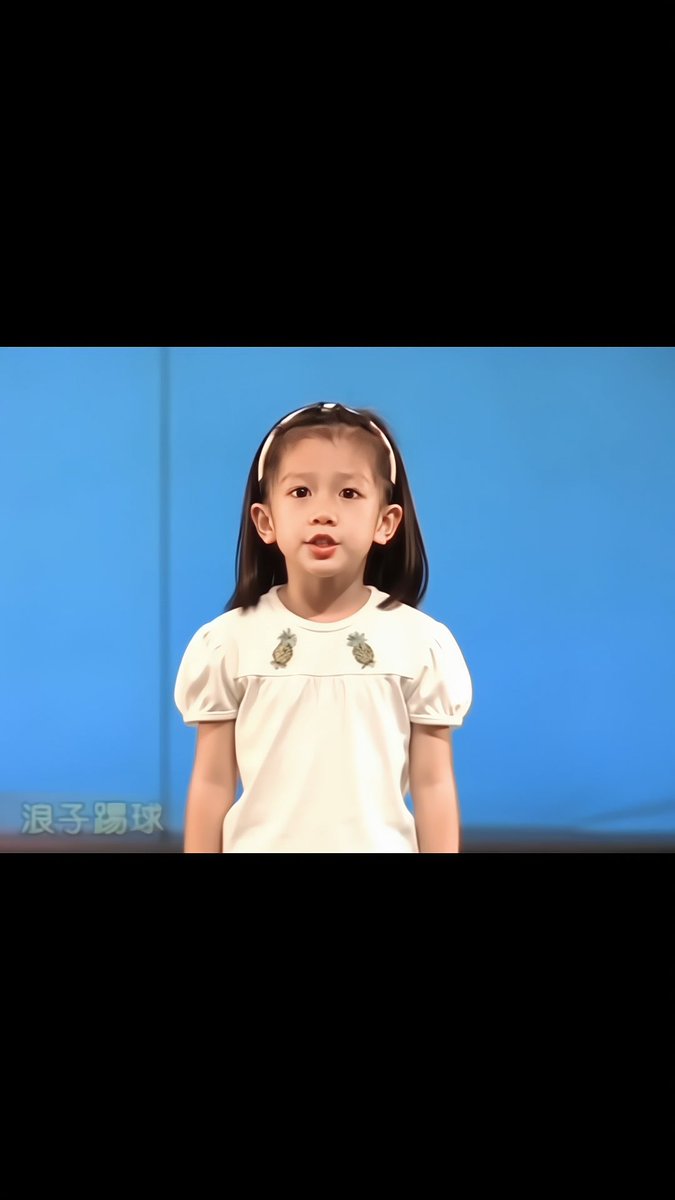 A young girl with a headband and a white shirt with pineapple embroidery stands against a blue background, with the Chinese text "浪子踢球" visible in the bottom left corner.