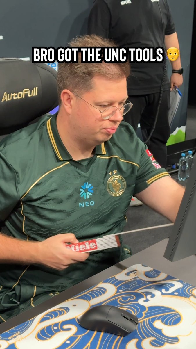 The image shows a man wearing a green and gold jersey with "NEO" and a team logo, looking down with a disappointed expression while holding a Twix candy bar at a gaming event, with the text "BRO GOT THE UNC TOOLS 😳" overlaid. The caption "All this to drop 2 kills in a half" humorously suggests that despite having all the "tools" (candy, setup, team jersey), his performance in the game was underwhelming.
