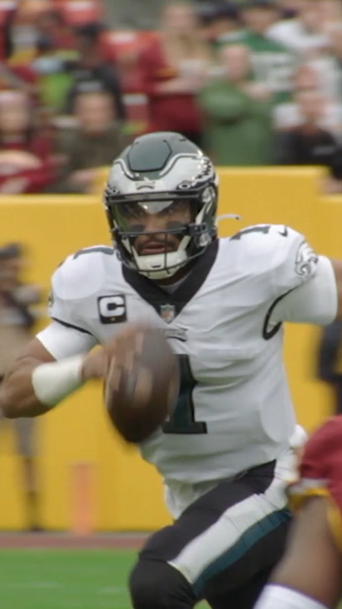 An NFL quarterback wearing a Philadelphia Eagles jersey with the number 1, scrambling with the football.