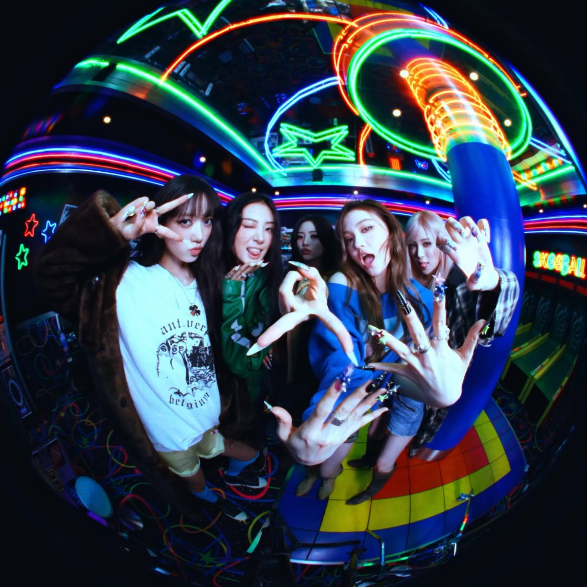 Five young women pose in a neon-lit arcade, making peace signs and claw gestures with elaborate long nails in front of a 'SKEEBALL' game.