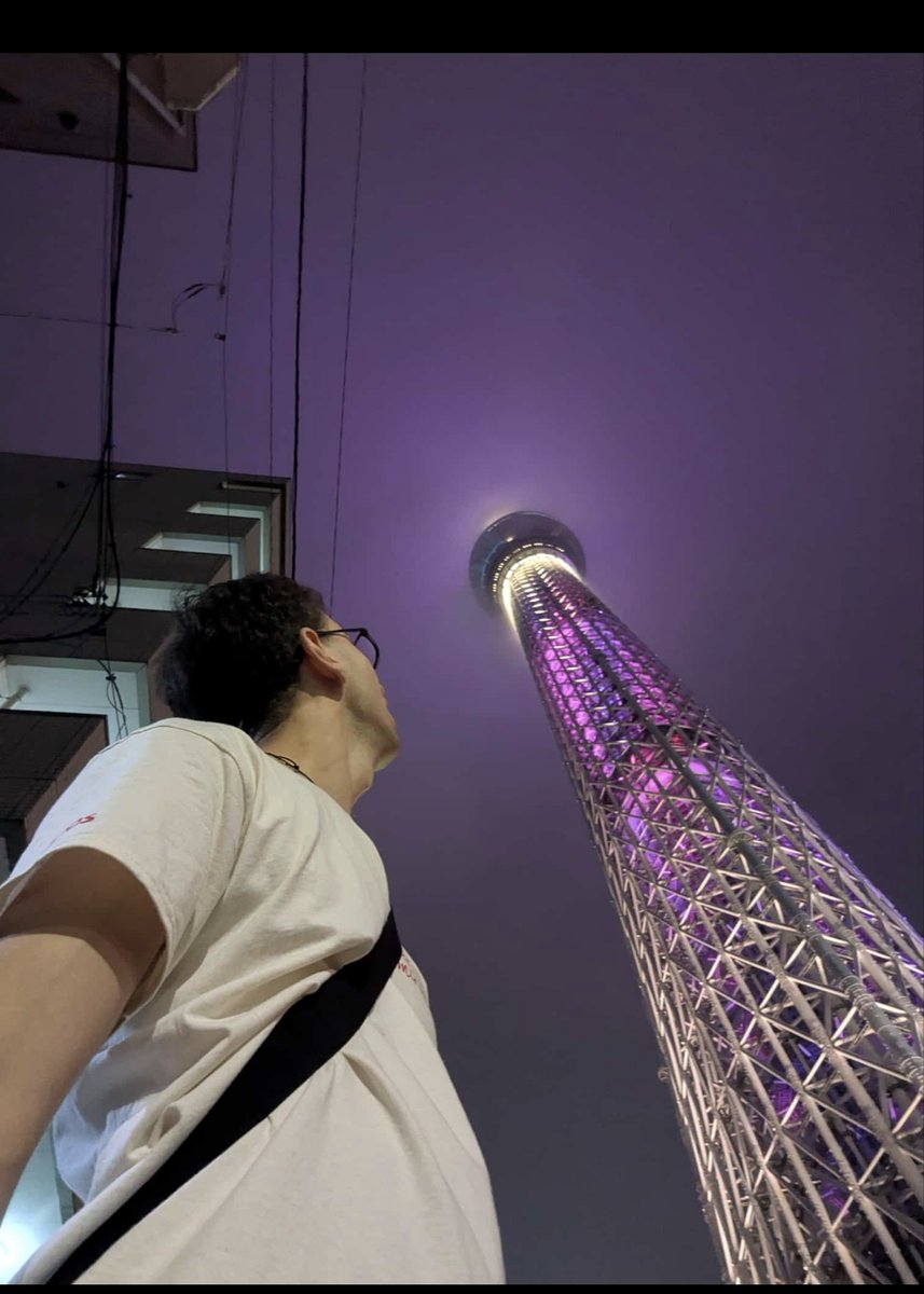 KatySnchez's tweet photo. Un nieto mirando hacia arriba desde la base de la Tokyo Skytree, la torre de radiodifusión y mirador iluminada de color púrpura #Tokio #torre #hacerfotos #japon https://t.co/ZwvRkc1xOR