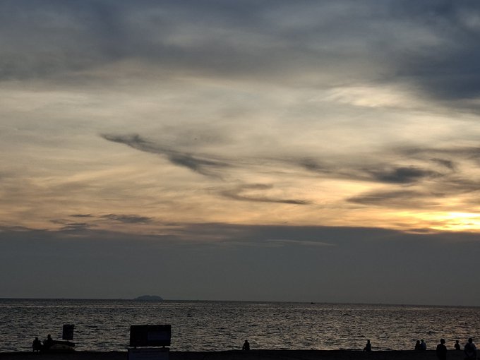 a sunset over a body of water with silhouettes of people and small islands on the horizon