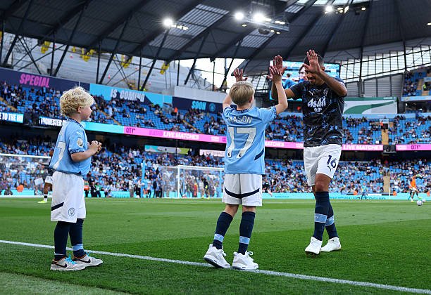 DeeTriumph's tweet photo. Rodri was so happy to see Kevin De Bruyne’s children, Romeo and Mason. 🥹🩵

Before walking out for warm-up, he played with them. After the warm-up, Mason raised his hand for Rodri to meet it — just like Rodri and De Bruyne used to do as substitutes. 😭

Mason is representing his father. 🩵

Rodri: “Mason, over to you now. Go and do it like your father.” 😂🩵