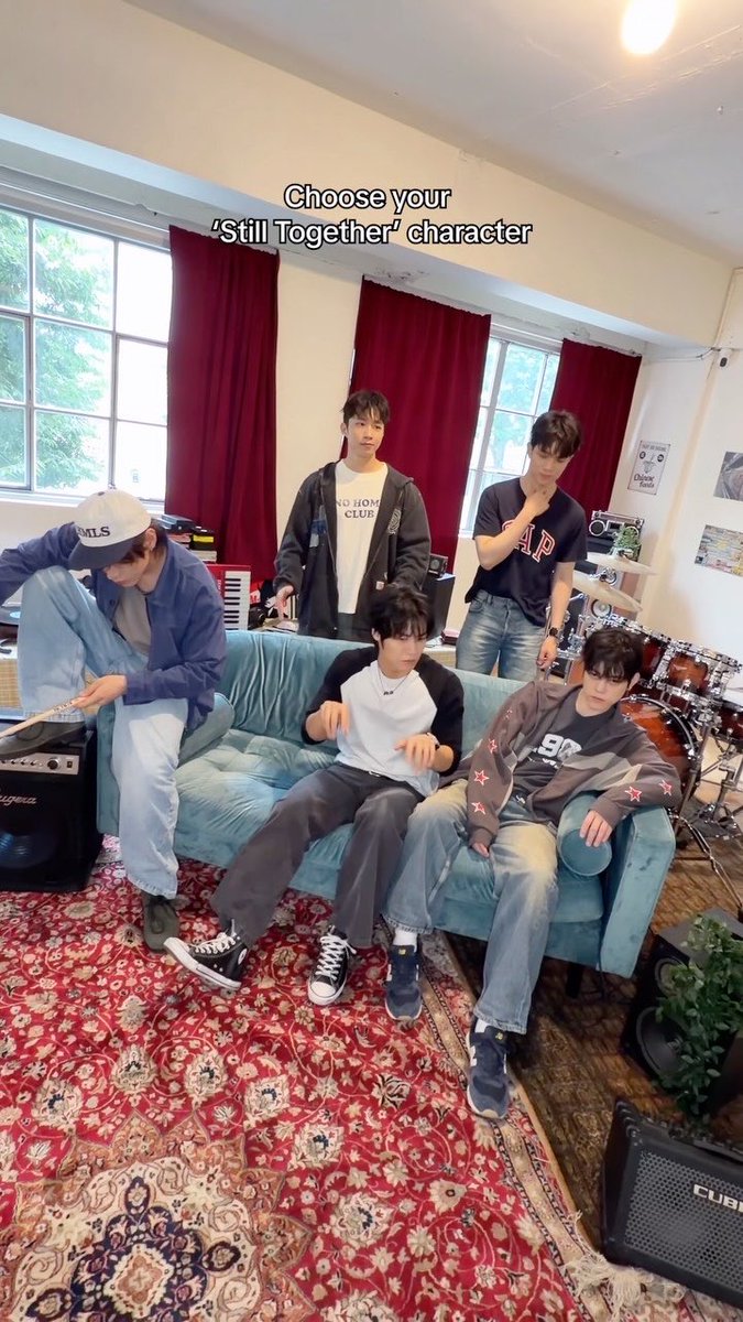 Five young men posing in a room with a blue couch and musical instruments, with text overlay reading 'Choose your 'Still Together' character'.