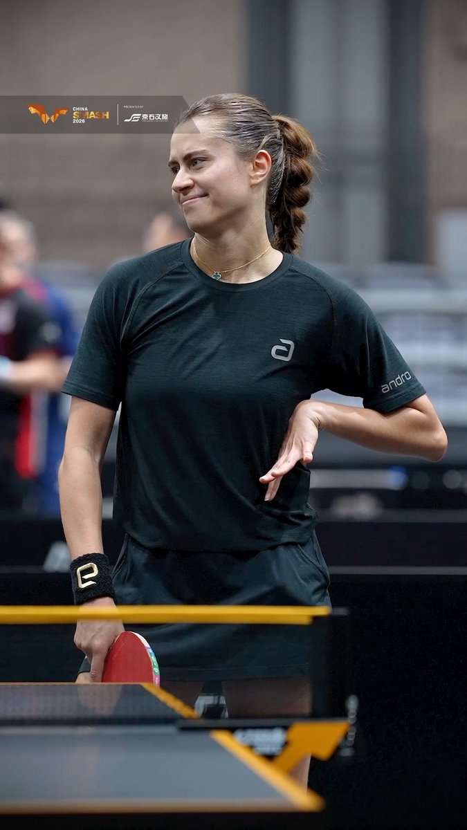 A female athlete in a black shirt and wristband, holding a ping pong paddle next to a table, with logos for 'W CHINA SMASH 2025' and other sponsors visible.