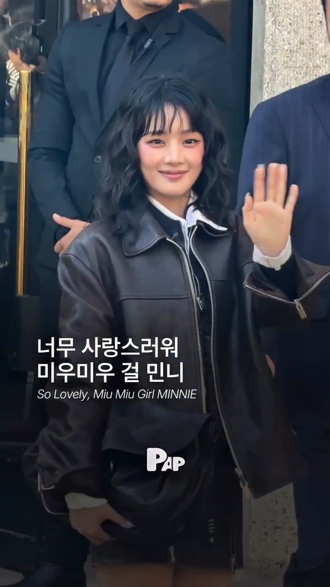 A young woman waves while wearing a brown leather jacket, accompanied by Korean text translating to 'So Lovely, Miu Miu Girl MINNIE' and a 'PAP' logo.