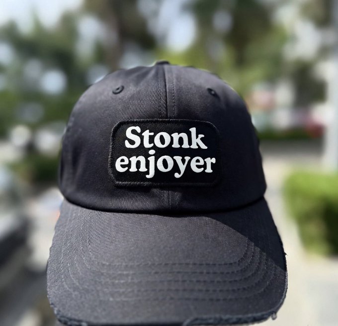 A close-up photo of a black baseball cap featuring a patch that reads 'Stonk enjoyer' in white text.
