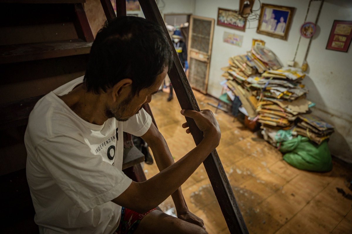 Mirror_org's tweet photo. เที่ยงคืนตีหนึ่ง ในยามใครคนอื่นหลับใหล เขามักออกไปเก็บของเก่า ที่ซูเปอร์มาร์เก็ตเจ้าประจำ
.
เพราะนั่นคือเวลา ที่พนักงานขนส่งจะขับรถมาลงของ
.
หลังกล่องบรรจุถูกกรีดแกะ ลำเลียงสินค้าเก็บเข้าคลัง เหลือไว้เพียงลังกระดาษ เขาค่อย ๆ จับรวบรวมมัน ผูกมัดด้วยเชือกฟาง แล้วนำข้ามสะพาน กลับบ้าน ก่อนฟ้าสาง
.
นั่นคือช่องทางทำกิน ของชายพิการ สายตาเลือนราง และอดีต เคยเป็นฝีในสมอง
.
โดยอาการโรคอย่างหลัง แม้รักษาจนเสร็จสิ้น แต่มันได้ทิ้งร่องรอย ความเสียหาย ให้ติดตัวตลอดมา
.
“ไม่มีแรงเหมือนเดิม” เขาพูดช้า คิดช้า ประมวลผลนานกว่าปกติ และนับแต่เกิดอุทกภัย เขา “ไม่ได้ออกไป (เก็บของเก่า) สี่วันแล้ว”
.
ชาวบ้านบางคนบอก “สองสามวันแรกน้ำเชี่ยว ดูทรงเขาน่าจะเดินไม่ไหว ขนาดผมร่างกายดี ๆ ยังเหนื่อยเลย”
.
เราหันมองสำรวจบริเวณชั้นหนึ่งของตัวบ้าน ซึ่งตั้งอยู่ในย่านชุมชนชายคลองบางบัว เห็นเครื่องเรือนทำจากไม้บวมน้ำ เห็นภาชนะใส่อาหารบูดเน่า ถุงข้าวแกงเต็มไปด้วยฝูงหนอนแมลงวัน เราเห็นขวดแก้วจำนวนหนึ่ง และกองลังกระดาษแฉะชื้น ที่หากนำไปชั่งกิโลฯ ขายตอนนี้ คงไม่มีที่ไหนรับ จะปล่อยไว้ก็มีโอกาสขึ้นรา แต่จะนำออกไปผึ่งตากก็ไม่ได้ เพราะข้างนอกนั้น ฝนยังโปรยปราย 
.
ถ้าไม่มีทีมอาสาล้างบ้านของมูลนิธิกระจกเงา “ผมก็คงจะล้างเองไปเรื่อย ๆ  ค่อย ๆ ทำไป มันมีของด้วย เลยต้องใช้เวลา ถ้าเมื่อก่อนไม่มีของ (ลังกระดาษ ขวดแก้ว โต๊ะตู้ชำรุด) ก็จะล้างได้อยู่ แต่ตอนนี้มี มันล้างยาก...”
.
“พี่ยังคิดอยู่ว่าจะทำยังไงดี” ญาติซึ่งอยู่บ้านห่างออกไป เปิดใจเล่าขณะเจ้าหน้าที่และอาสากำลังลงแรงล้างบ้าน เคลียร์ขยะ ให้ชายพิการ เธอบอก “พี่เพิ่งล้างบ้านของพี่เสร็จ ส่วนบ้านเขา คือ พวกคราบน้ำมันต่าง ๆ ลอยเต็มไปหมด พี่ยังไม่รู้เลยว่าจะล้างยังไง
.
“เขาป่วย เขาอยู่คนเดียว เราเป็นญาติก็จริง แต่บางทีเราก็มีข้อจำกัด อย่างวันนี้พี่ลางาน เลยพอจะดูแลเขาได้ ส่วนวันอื่นที่ต้องทำงาน พี่จะไม่สามารถไปดูแลเขาได้เลย
.
“ก็กะรอน้ำแห้งแล้วค่อยขัดค่อยถู หรือยังไงก็ยังไม่รู้ ยังคิดไม่ออก แต่เจ้าหน้าที่กระจกเงามาก่อน เมื่อเช้าได้ข่าวว่ามูลนิธิจะมาช่วยทำความสะอาดที่บ้านให้พอดี โอ้โห แฮปปีมาก
.
“ดีมาก
.
“มีหน่วยงานอาสามาล้างบ้านให้
.
“มันดีกับคนไม่มีที่พึ่งจริง ๆ”

_______________

ระดับน้ำในหลายพื้นที่ลดลง แต่แม้จะลงแรงล้างบ้าน ขัดถูทำความสะอาดจนหมดจดอย่างไร บ้านของผู้ประสบภัยที่เราเข้าไปดูแล หลายหลัง ก็กลับยังไม่ใช่บ้าน อย่างที่พร้อมอยู่อาศัย

มูลนิธิกระจกเงา ขอเปิดระดม เครื่องนอน หมอน ผ้าห่ม โต๊ะอเนกประสงค์ ตู้เสื้อผ้ามีซิป ตู้ลิ้นชักพลาสติก ทั้งเก่าใหม่ เพื่อเป็นของตั้งต้น ให้ผู้ประสบภัยกลุ่มเปราะบาง จากสถานการณ์น้ำท่วมกรุงเทพ สามารถกลับไปใช้ชีวิต ในบ้านของพวกเขาได้อีกครั้ง

บริจาคได้ที่
มูลนิธิกระจกเงา เลขที่ 191 
ซอย วิภาวดีรังสิต 62 แยก 4-7 
แขวงตลาดบางเขน เขตหลักสี่ กทม. 10210
โทร. 06 1909 1840, 06 3931 6340

หรือสนับสนุนภารกิจล้างบ้าน
ได้ที่ กองทุนภัยพิบัติ (Special Force) 
โดยมูลนิธิกระจกเงา
เลขที่บัญชี 202-258298-3 ธ.ไทยพาณิชย์
.
#น้ำท่วมกรุงเทพ #มูลนิธิกระจกเงา