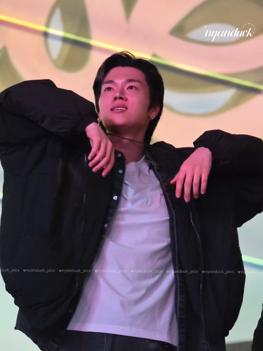 A young man with dark hair, wearing a black jacket over a white shirt, poses with his hands raised near his neck during what appears to be a fan event, with a decorative background featuring eye-like designs and "nyanduck" watermarks visible.

The image aligns with the post's mention of "XdineryHeroes" (엑스디너리히어로즈) and member "Jungsu" (정수), showing him performing at the event dated 261004 (October 4, 2026).