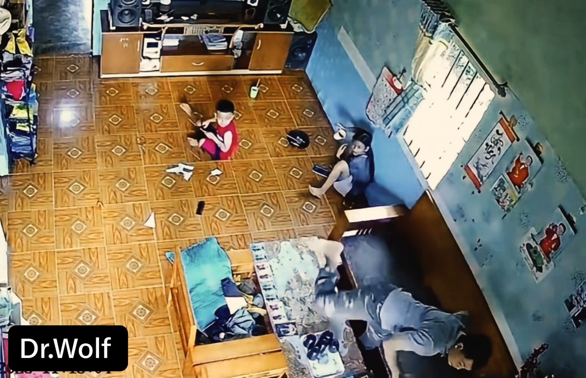 Surveillance camera footage showing a room interior with children and adults on a patterned tile floor, labeled 'Dr.Wolf' in the bottom left corner.