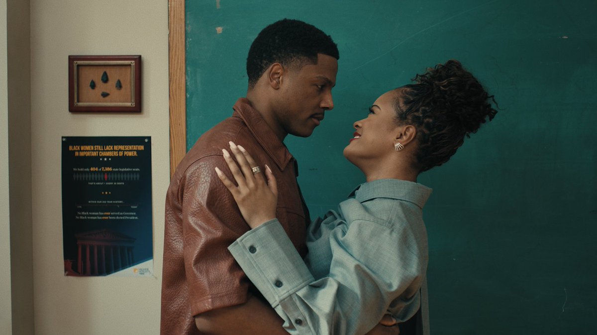 A Black couple shares an intimate moment in front of a chalkboard, with the woman gazing up at her partner. On the wall beside them, a framed artwork and an infographic poster are visible, the latter reading "BLACK WOMEN STILL LACK REPRESENTATION IN IMPORTANT CHAMBERS OF POWER" and featuring statistics like "404 of 7,386 state legislative seats" alongside an image of a government building—contextualizing the post's "NEW LOVE TRIANGLE UNLOCKED" announcement, suggesting this couple's relationship will intersect with themes of political power dynamics.