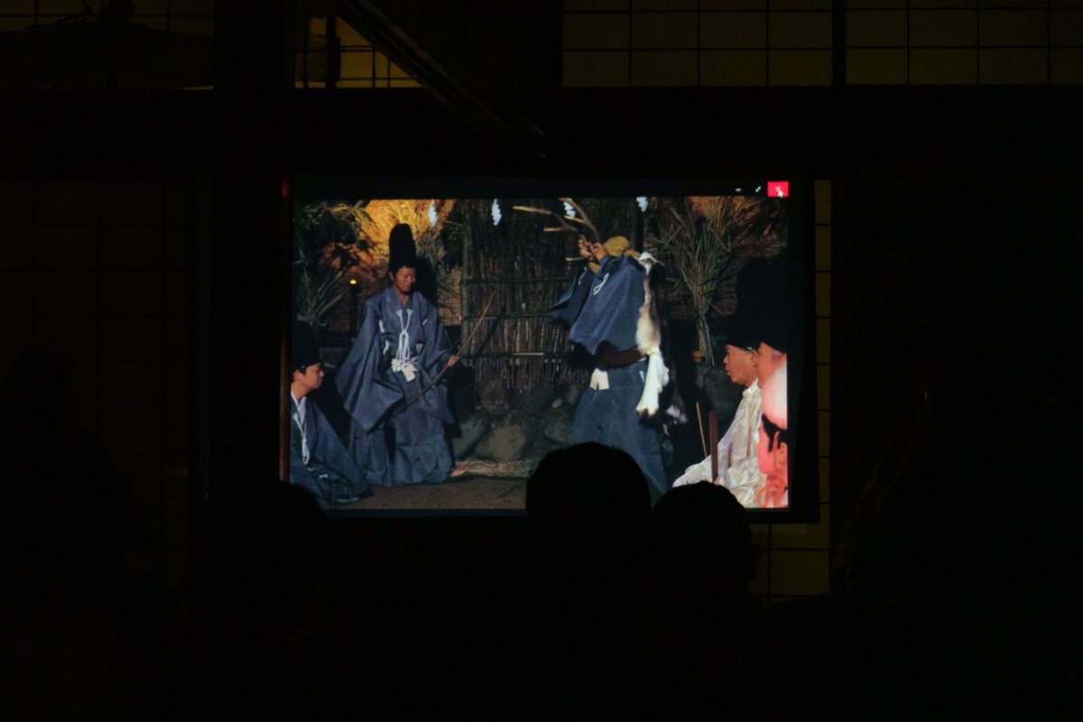 miyoshinsai's tweet photo. 諏訪の大祝邸の再始動に関連した企画、映画「鹿の国」の弘理子監督と、スワニミズム原直正会長、石埜三千穂事務局長とのパネルディスカッション。久々に弘監督にお会いしに行きました。

道が混んでいて少し遅刻。大祝邸の畳の間を三部屋つなげた会場は満員御礼。一番後ろに着座。まずは「鹿の国」の酉の祭りのシーンが流れました。

この参列者でひしめく長細い空間、なんだか十間廊に似ている・・・スクリーンでは宮司が鹿の頭を献饌し、典儀の「お頭をお下げください」の声に、思わず低頭しそうになりました。

そして、御室の芸能の再現シーン。狭くて暗い部屋の奥のスクリーンでは、なんだか知ってる人が鹿打ちの踊りを踊っています。御室神事の同席者にはこういう風に見えるのだろうな、と客観視できて面白かったです。

後半の部のパネルディスカッションは、大祝の居館が前宮神殿（ごうどの）から宮田渡（みやたど＝現在の大祝邸）へ移った歴史的経緯を中心に意見が飛び交いました。いろいろ説はありますが、神殿を移した最大のきっかけは、大祝による狂気の犯罪、文明の内訌でしょう。諏訪の大祝と惣領が別行動を取り始めた文明年間の頃、大祝が惣領家など一族衆を神殿に招いて、酒宴の最中に殺戮するという事件が起きました。唯一生き残った惣領家の次男・宮法師丸を旗頭に、諏訪の五官祝たちが大祝継満を干沢城に攻め、高遠へ追い出します。ついでに書くと、その混乱に乗じて挙兵した下社大祝金刺興春を破って下社を焼き払いました。大祝は惣領の宮法師丸（頼満）が兼任し、血に塗れた神殿を捨て桑原城へ移りました。神都諏訪といえども、戦国乱世の風潮には逆らえず、内紛を繰り返し低迷しているうちに、隣国武田に攻め取られました。その後はご存知の通り、武田が織田に滅ぼされ、直後に織田が滅んで北条と徳川に切り取られ、徳川が関東に移った後は豊臣に支配され。諏訪惣領家が諏訪に戻ってきたのは、関ヶ原の合戦で東軍が勝った後のことなのです。そもそもその混乱期には大祝がまともに祭祀をできていたとは思えません。大祝居館が現在の位置で再興したのも、関ヶ原の後なのでしょうね。

今回、原会長が配布してくれた資料は、分かりやすく纏められていて、とても勉強になりました。もらえた人は幸運でしたね。

大祝邸は平成で無人になりましたが、まさか祭壇の前でこのようなイベントが行われる世になるとは、思ってもみなかったでしょう。再び日の目をみることになったなんて、きっと大祝の御霊も喜んでおられることでしょうね。