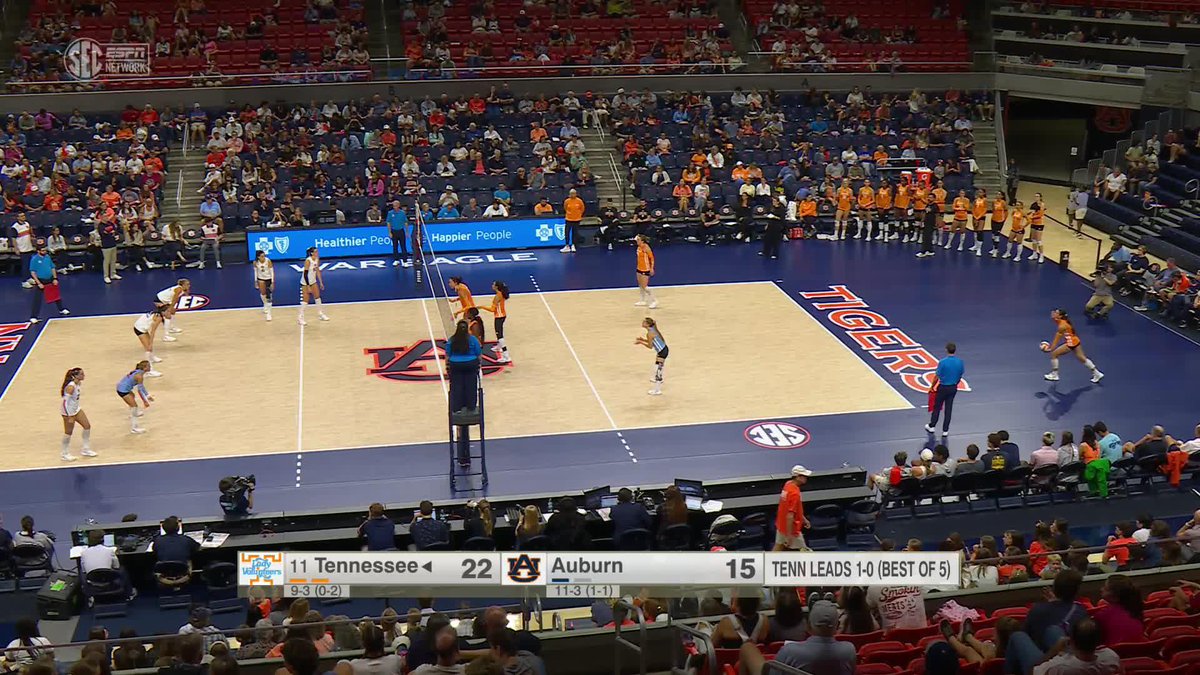 A women's college volleyball match between #11 Tennessee and Auburn at an arena, with the scoreboard showing Tennessee leading 22-15 in a 'TENN LEADS 1-0 (BEST OF 5)' series, set on a court featuring 'TIGERS' and 'AUBURN' branding.