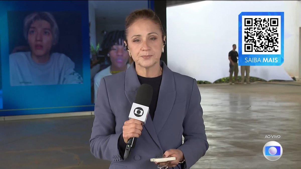 A female TV Globo reporter in a gray blazer holds a microphone during a live broadcast ("AO VIVO") featuring a QR code labeled "SAIBA MAIS," while background screens display election-related imagery, aligning with the station's "GIRO ELEIÇÕES 2026" coverage.