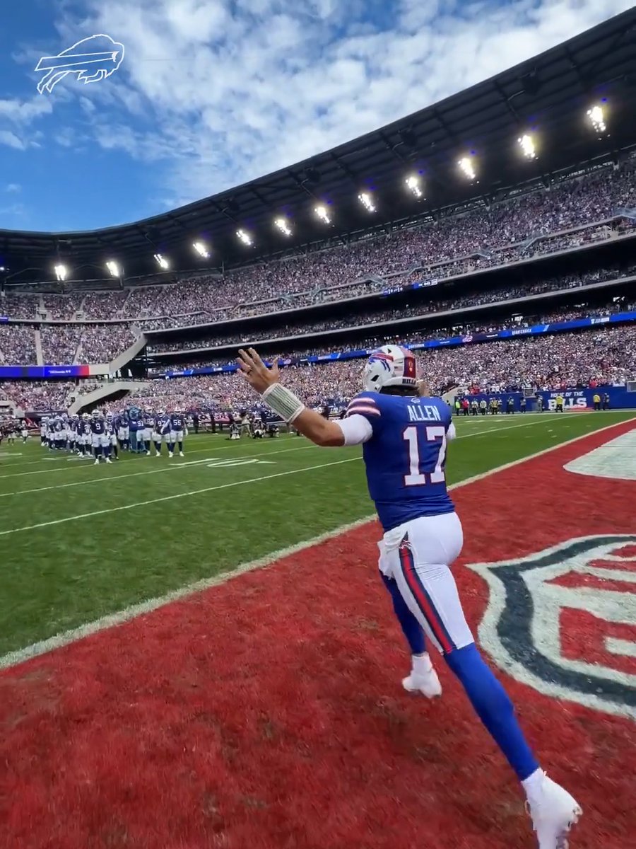 Buffalo Bills quarterback Josh Allen (#17) walks onto the field at Highmark Stadium with his arm raised, hyping up the sold-out crowd ahead of the matchup against the New England Patriots.