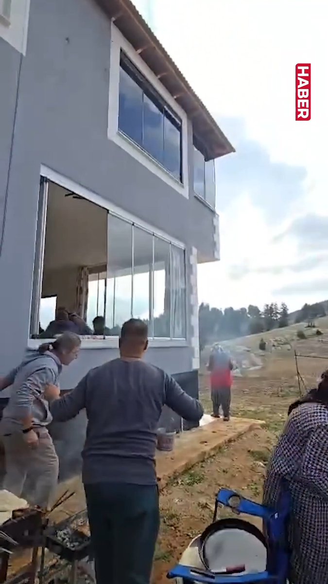 The image captures the moment a family at a barbecue outdoors in a rural area reacts to an earthquake, with the "HABER" news logo visible in the corner, aligning with the post's description of the earthquake being caught on camera and causing panic during their outdoor activity.
