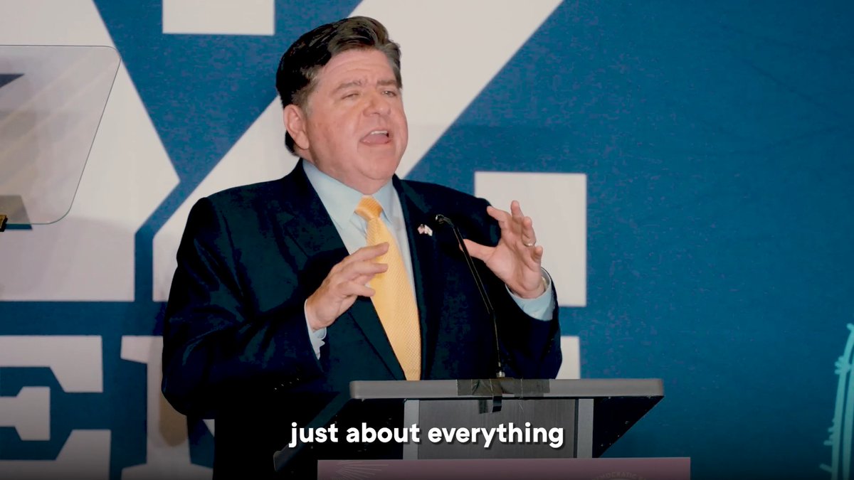 A man in a dark suit and yellow tie speaks passionately at a lectern against a blue and white backdrop, with the caption 'just about everything' visible at the bottom.