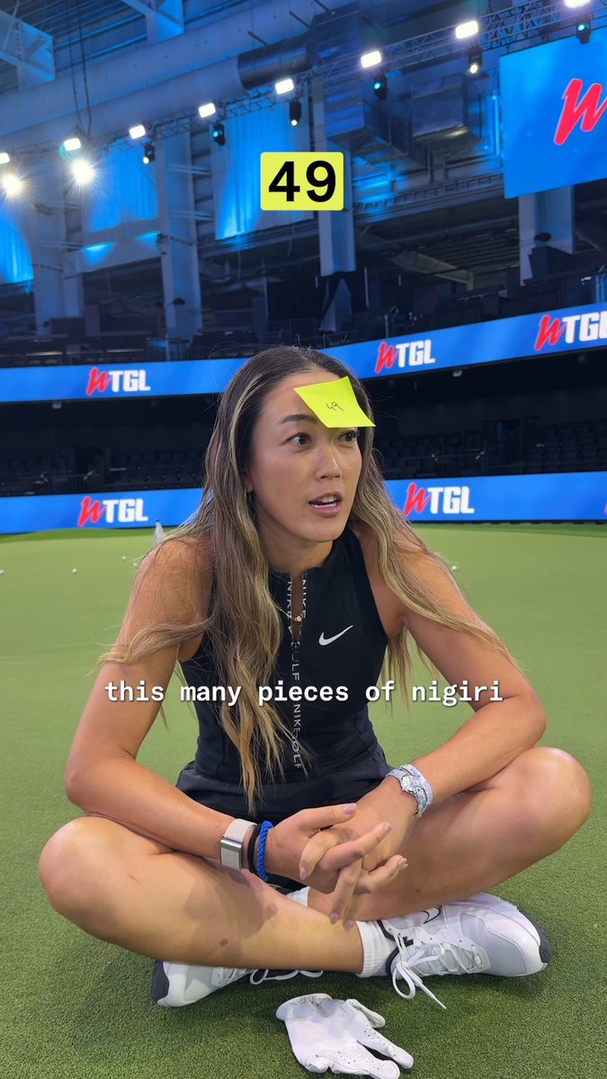 A female athlete sitting on a TGL indoor golf course with a sticky note showing '49' on her forehead, captioned 'this many pieces of nigiri'.