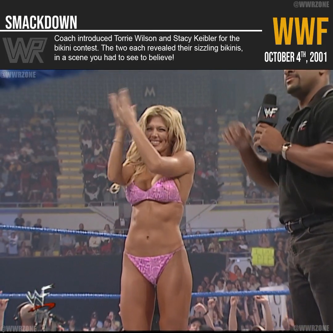 The image, captioned "WWF SmackDown" and dated "October 4th, 2001," shows a blonde woman in a pink leopard-print bikini clapping and smiling in a wrestling ring alongside an announcer holding a WWF microphone. The accompanying text confirms this is from the bikini contest where Torrie Wilson and Stacy Keibler were introduced by Coach.