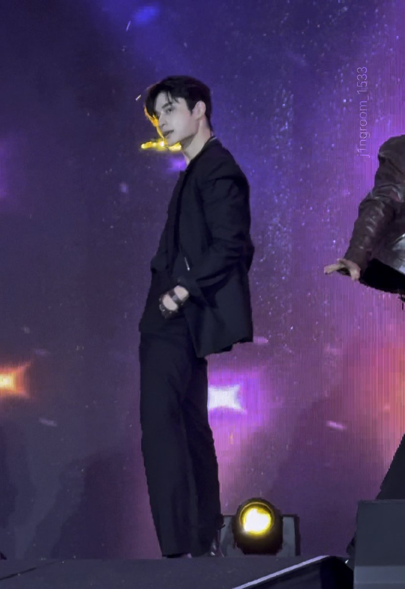 A male performer, appearing to be a K-pop idol, stands on stage in an all-black suit, looking back over his shoulder against a purple, starry backdrop. The watermark 'j7ngroom_1533' is visible in the upper right.