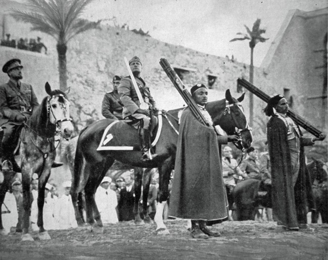 MesveretX's tweet photo. Benito Mussolini'nin siparişi üzerine hazırlanmış olan "İslam'ın Kılıcı", Faşist İtalya'nın Libya'daki hakimiyetini pekiştirmek ve İngiltere ile Fransa'nın topraklarında yaşayan Müslümanlara ulaşmak amacıyla tasarlanan bir propaganda malzemesiydi. 

Mussolini için fazlasıyla önemli olan Müslüman halkın desteği konusu, kendisinin "İslam'ın Koruyucusu" olarak ilan edilmesiyle daha da açığa çıkmıştı.

İtalyan devletinin Libya'da kalıcı olması ve otorite kurması için Kur'an okulları ve camiiler inşa ettiren Mussolini, 1937 yılında Trablus'a görkemli bir ziyaret düzenledi ve propaganda makinesi için bu ziyareti kullandı.