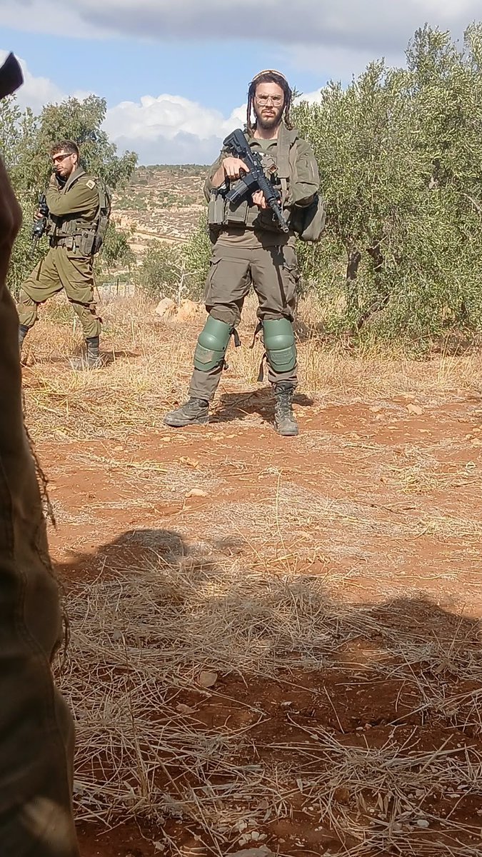 QudsNen's tweet photo. An Israeli settler dressed in military uniform helps Israeli forces prevent Palestinian farmers from harvesting olives in Beit Furik, east of Nablus in the occupied West Bank. https://t.co/yS8thWpbdZ