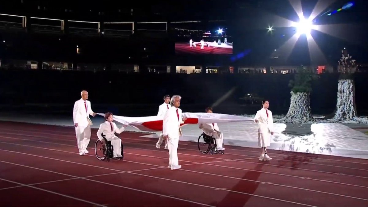 ArchiveInt's tweet photo. The Japanese flag now enters the stadium, and what will follow afterwards is the raising of the flag as the Kimigayo blares out.

#AichiNagoya2026   #ImagineOneHeart https://t.co/yYWDSJ1Sca